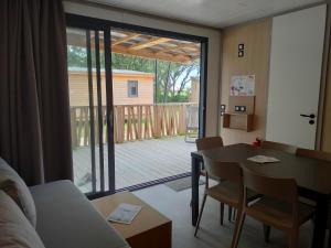 a living room with a table and a view of a deck at VVF Les Sableaux à Noirmoutier in Le Grand Vieil