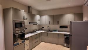 a kitchen with stainless steel appliances and white cabinets at كمباوند ماربيلا الكورنيش شقة in Ar Rākah