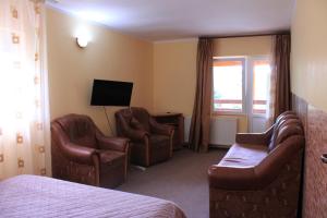 a hotel room with two chairs and a bed and a television at Pension Belmonte in Sâmbăta de Sus