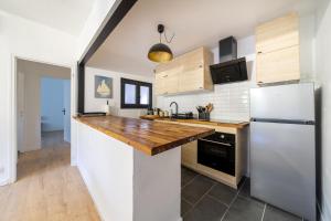 a kitchen with a wooden counter top and a refrigerator at L'Écrin de Beaucaire - Climatisé à 30 min dArles in Beaucaire +6 photos