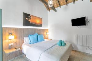 a bedroom with a large white bed with blue pillows at Casa Mica Relax y Naturaleza in Vega de San Mateo +19 photos