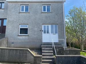 a house with a white door and stairs at Summerdale Kirkwall in Orkney