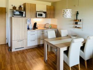 a kitchen with a wooden table and white chairs at Gemütliche Wohnung mit schöner Aussicht in Haidmühle