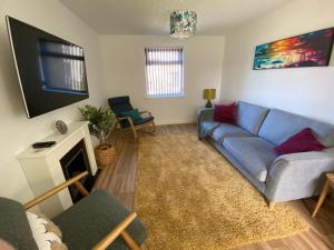 a living room with a blue couch and a tv at Summerdale Kirkwall in Orkney