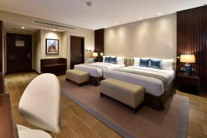a hotel room with two beds and two chairs at Bahrain Airport Hotel Airside Hotel for Transiting and Departing Passengers only in Muharraq