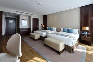 a hotel room with two beds and chairs in it at Bahrain Airport Hotel Airside Hotel for Transiting and Departing Passengers only in Muharraq