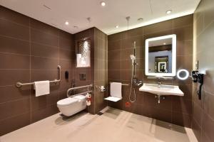 a bathroom with a toilet and a sink and a mirror at Bahrain Airport Hotel Airside Hotel for Transiting and Departing Passengers only in Muharraq