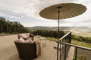 a chair and an umbrella on a balcony at Exklusives Ferienhaus in Alleinlage mit privater Sauna - La petite maison in Straden