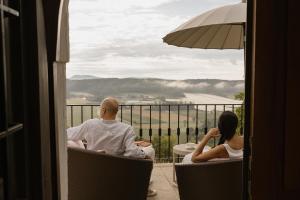 a man and a woman sitting in chairs on a balcony at Exklusives Ferienhaus in Alleinlage mit privater Sauna - La petite maison in Straden
