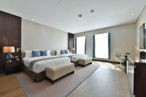 a large hotel room with two beds with blue pillows at Bahrain Airport Hotel Airside Hotel for Transiting and Departing Passengers only in Muharraq