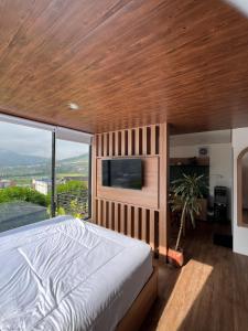 a bedroom with a large bed and a flat screen tv at Ullasa Villa Dieng in Diyeng