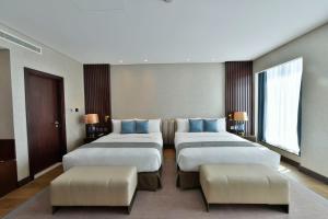 a hotel room with four beds and two ottoman at Bahrain Airport Hotel Airside Hotel for Transiting and Departing Passengers only in Muharraq