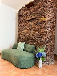 a green couch in a room with a stone wall at Hotel Residence Eden in Palinuro