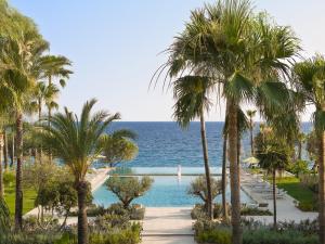 Una vista del océano desde un resort con palmeras. en Grecotel Filoxenia, en Kalamata