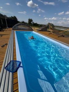 a person swimming in a large blue swimming pool at Мій Еко Готель in Fominka