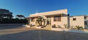 a white house with a palm tree in the driveway at Podilimbo - Ilios e Thalassa in Paestum