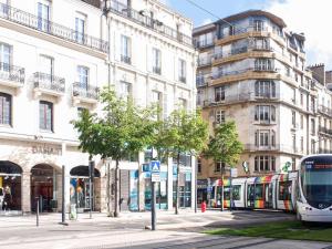Un autobús que circula por una calle junto a edificios altos. en Mercure Angers Centre Gare, en Angers