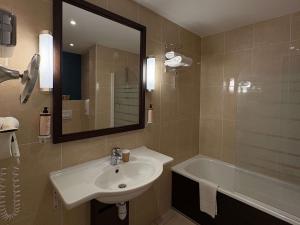 Un baño con lavabo, bañera y espejo. en Mercure Angers Centre Gare, en Angers