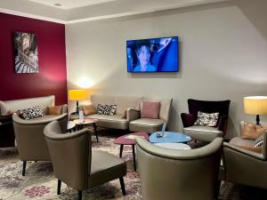 una sala de espera con sofás y TV de pantalla plana. en Mercure Angers Centre Gare, en Angers