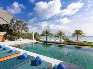 攀瓦海滩Pullman Phuket Panwa Beach Resort的一个带蓝色躺椅的游泳池和大海