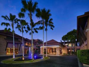 攀瓦海滩Pullman Phuket Panwa Beach Resort的一座楼前种有棕榈树的庭院