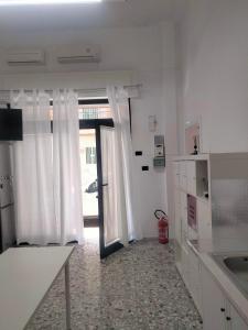 a kitchen with white walls and a door with curtains at Dolce Riposo in Trani