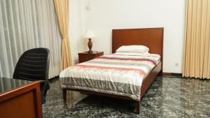 a bedroom with a bed and a table and a chair at The Sinabung Residence Jakarta in Jakarta