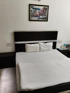 加姆布Hotel AMAR VILAS的卧室配有一张白色床,墙上挂着一幅画