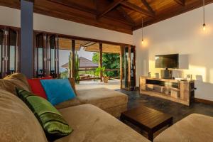 a living room with a couch and a television at 4 Bedroom villa with stunning sea & sunset view in Haad Yao
