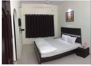 加姆布Hotel AMAR VILAS的一间卧室配有床和黑色窗帘
