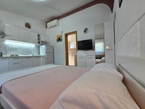 a white room with a bed and a kitchen at Apartments Villa Bazilika in Sečovlje