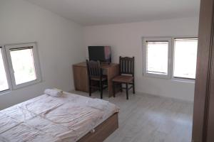 a bedroom with a bed and a desk and windows at Къща за гости Гергана in Raduil