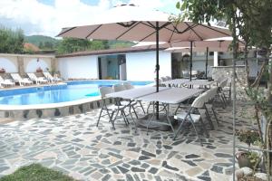a table with an umbrella next to a swimming pool at Къща за гости Гергана in Raduil