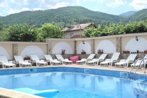 a pool at a hotel with chairs and a mountain at Къща за гости Гергана in Raduil
