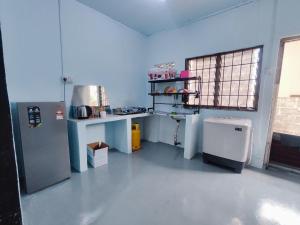 a kitchen with a refrigerator and a table in a room at BUDGET Homestay RumahTamu TELIPOT Kota Bharu in Kota Bharu