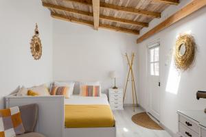 a bedroom with white walls and a bed with a yellow blanket at GuestReady - Exceptional house near Colares in Colares