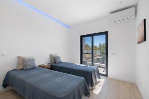 een witte kamer met 2 bedden en een raam bij V3 Atlantida Farm in Quelfes +34 foto's