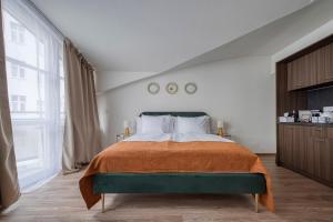 a bedroom with a large bed with an orange blanket at Anmut by Revelton in Karlovy Vary