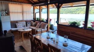 ein Wohnzimmer mit einem Tisch und Blick auf das Wasser in der Unterkunft Splav Panda in Perućac