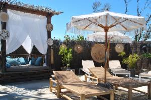 a patio with chairs and an umbrella and a bed at CAPAO Beach Hôtel in Cap d'Agde
