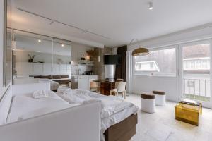 a white bedroom with a bed and a kitchen at Huswell Studio 14 in Knokke-Heist
