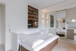a white bedroom with a large bed and a mirror at Huswell Studio 14 in Knokke-Heist