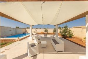 ein großer weißer Sonnenschirm auf einer Terrasse mit Pool in der Unterkunft Villa Respiro Di Puglia in Marina di Mancaversa