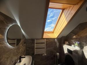 a bathroom with a skylight and a sink and a mirror at Noclegi Margo Dębno in Dębno +65 photos