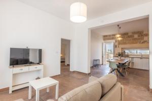 ein Wohnzimmer mit einer Couch, einem Fernseher und einem Tisch in der Unterkunft Villa Respiro Di Puglia in Marina di Mancaversa