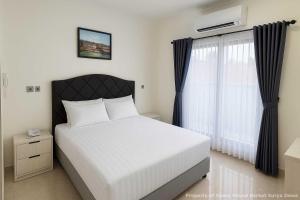a bedroom with a white bed and a window at Berkat Surya Dewa Guest House in Benuaanyar