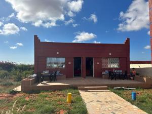 a red building with tables and chairs in front of it at Ferme touristique domaine BENJDYA à HAD SOUALEM in Berrechid