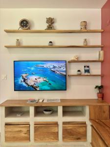 a flat screen tv on a wall with shelves at Sunset Dream - Bungalow haut de gamme proche Plage in Grand-Bourg +22 photos