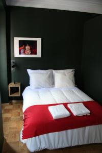 Una cama roja y blanca con dos toallas blancas. en 2U Oporto Urban Stays, en Oporto