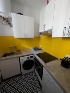 a kitchen with white cabinets and a sink and a dishwasher at Cozy Apartment in Simmering in Vienna